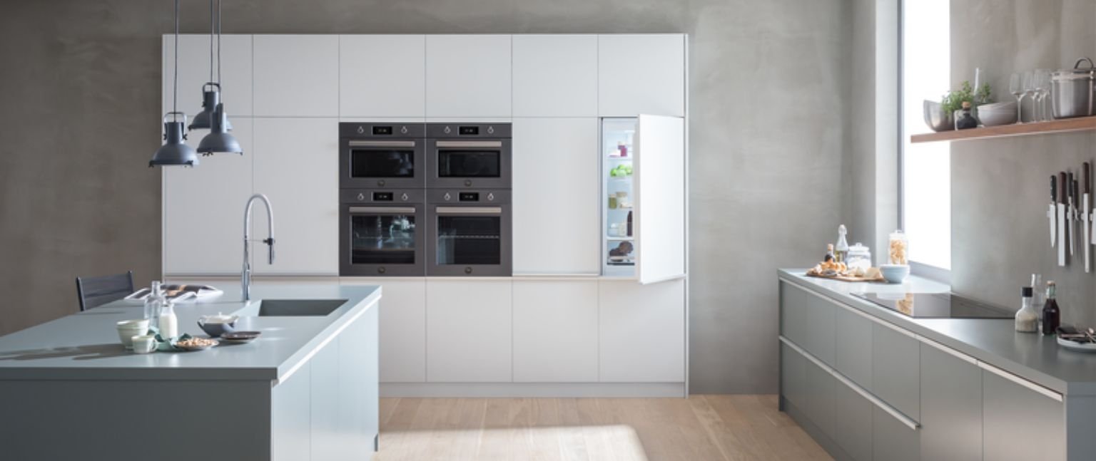 Minimal λευκή κουζίνα με εντοιχιζόμενες συσκευές Bertazzoni, διπλούς φούρνους και εντοιχιζόμενο ψυγείο με ανοιχτή πόρτα